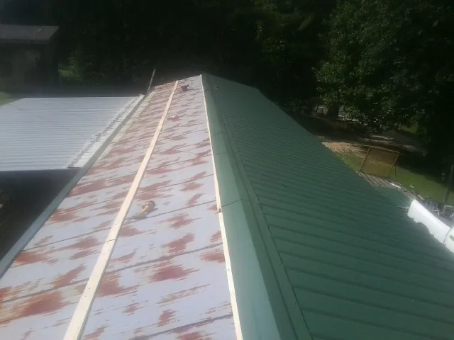 Old rusted panels beside newly installed green metal roofing — Wind Damage Roof Repair by Roofing Brothers in Elk Grove