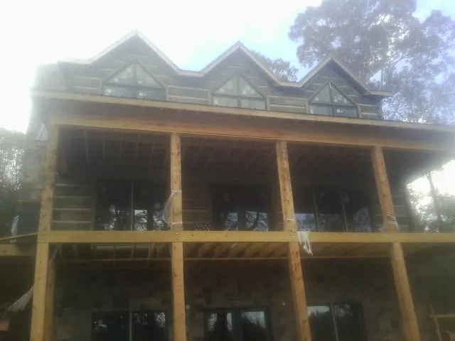 Dormers and porch framing on a large log home under construction — Roof Coating work by our crew in Elk Grove
