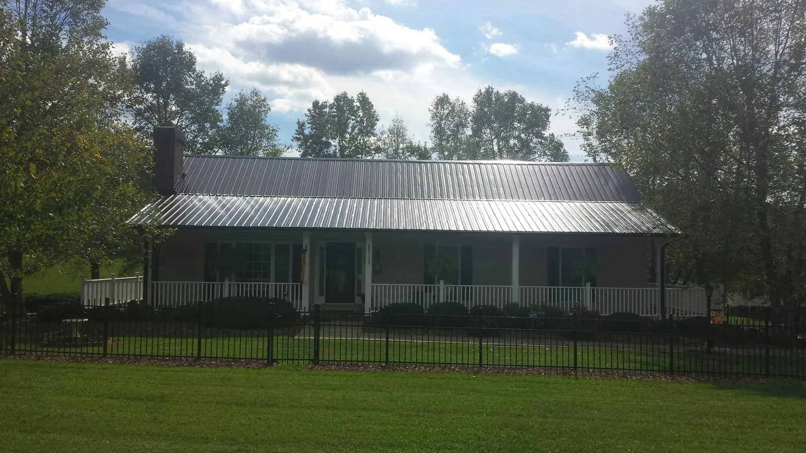Gray metal roof on a brick ranch with a full width front porch — Gutter Guard Installation work by our crew in Elk Grove