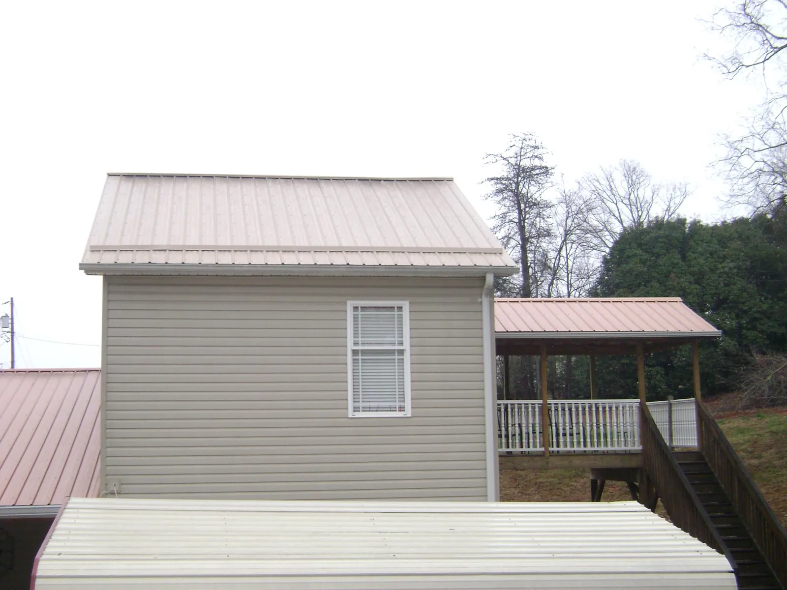 Tan metal roofs on a two story addition and attached porch, from a Roof Replacement job in Elk Grove