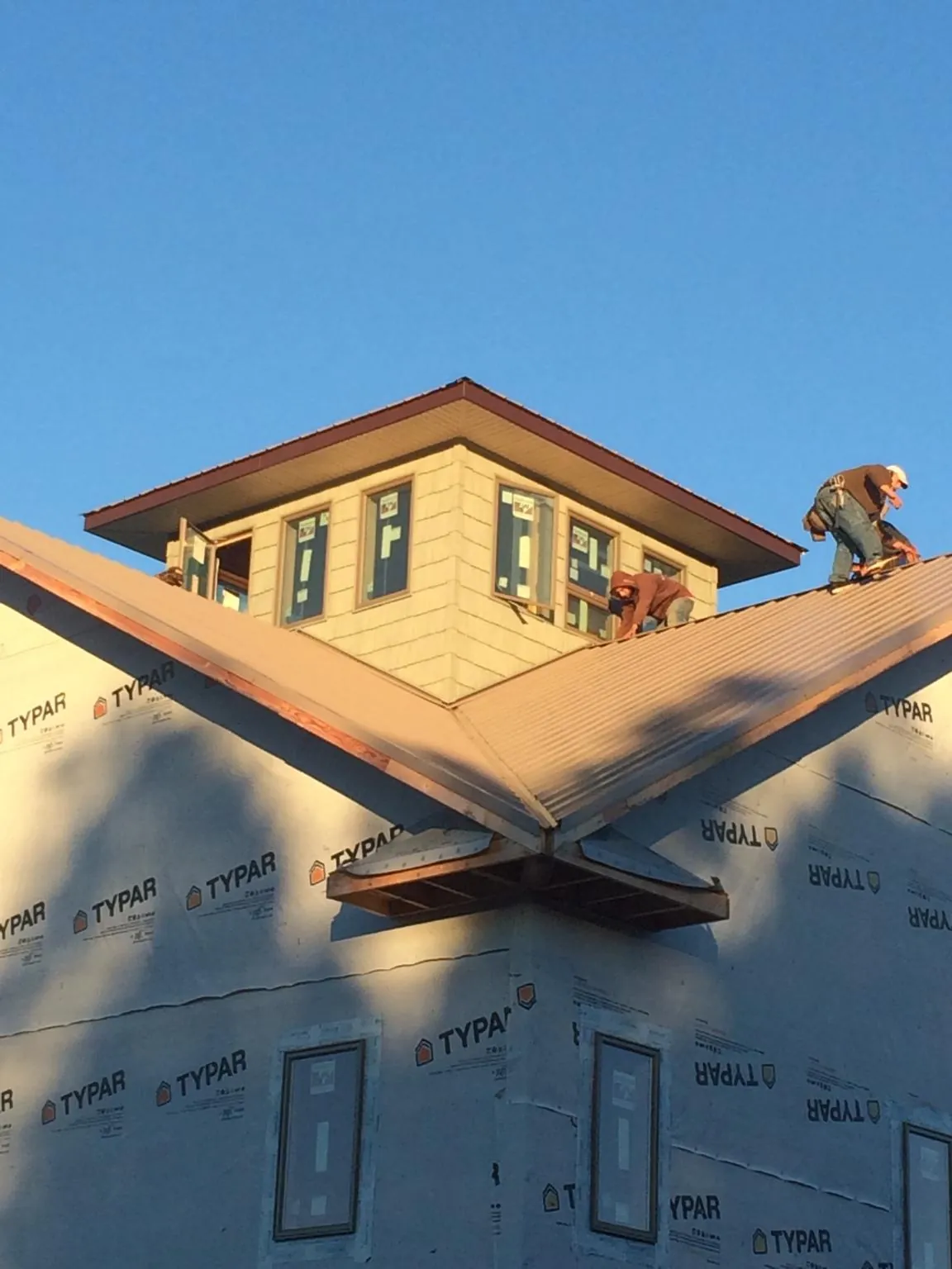 Roofers working around a rooftop cupola on a new metal roof at sunset — Roof Waterproofing in Elk Grove by Roofing Brothers
